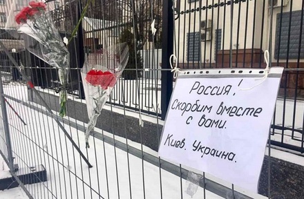 Жители Киева несут цветы и свечи к зданию посольства России